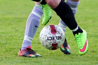 Jalkapallo pelissä kahden pelaajan jalkojen keskellä