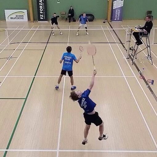 Sulkapallokilpailun nelinpeli, jossa yksi pelaaja lyö hyppysmashiä ja hänen parinsa vahtii etukenttää. Toisen puolen pari puolustaa vierekkäin. Tuomari tarkkailee peliä tuomarituolista.