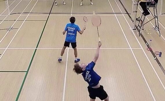 Sulkapallokilpailun nelinpeli, jossa yksi pelaaja lyö hyppysmashiä ja hänen parinsa vahtii etukenttää. Toisen puolen pari puolustaa vierekkäin. Tuomari tarkkailee peliä tuomarituolista.